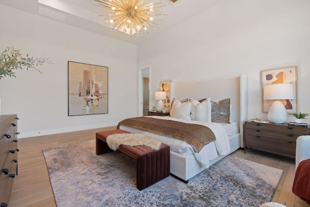 6013 Silver Luna Way, Austin, TX 78738 - bedroom featuring an inviting chandelier, baseboards, light wood-type flooring, a towering ceiling, and visible vents