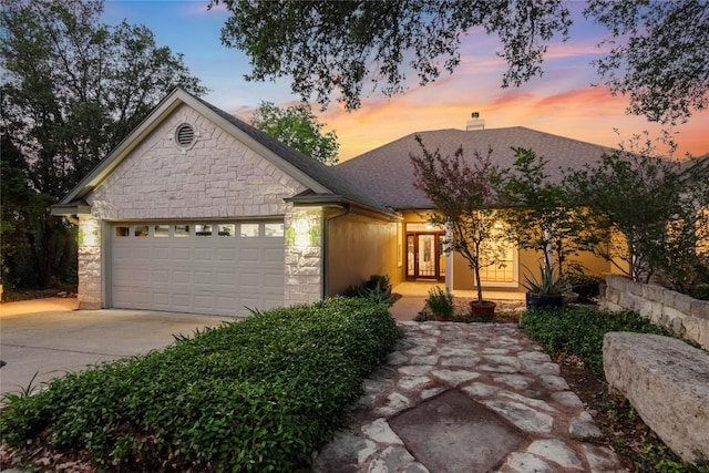 view of front facade featuring an attached garage, driveway, a chimney, and stone siding