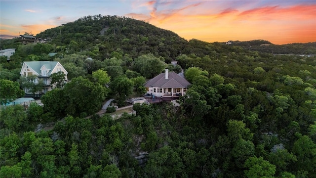 aerial view at dusk featuring a wooded view