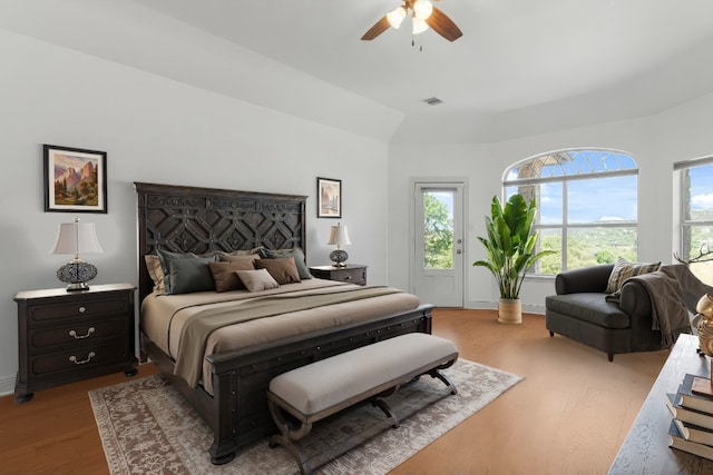 bedroom featuring visible vents, lofted ceiling, wood finished floors, baseboards, and a ceiling fan
