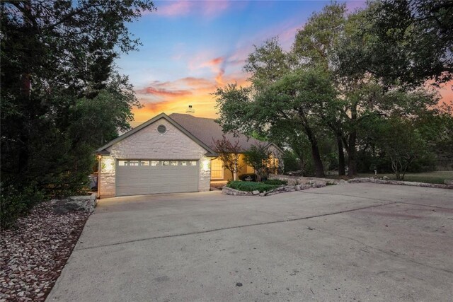 ranch-style home featuring a garage, stone siding, and concrete driveway