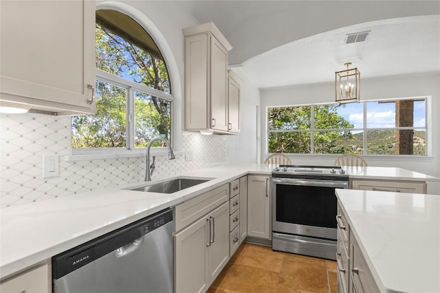 kitchen featuring decorative backsplash, visible vents, appliances with stainless steel finishes, a sink, and a notable chandelier