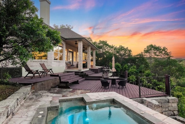 pool at dusk featuring a fenced in pool, a ceiling fan, a patio area, and a deck