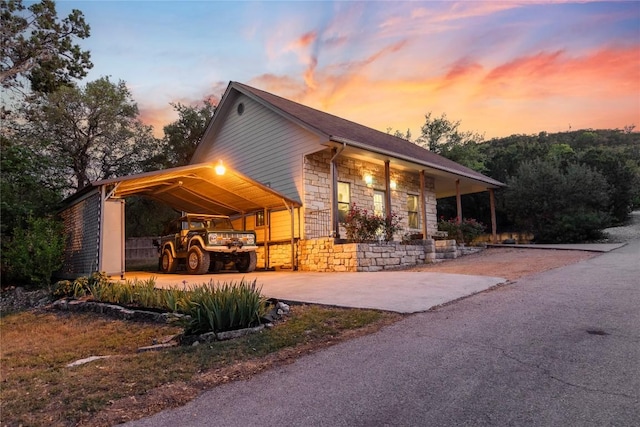 18408 W Rim Dr, Jonestown, TX 78645 - view of front of house featuring stone siding, a carport, covered porch, and driveway