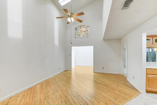 8518 Fathom Cir Unit 107, Austin, TX 78750 - unfurnished living room featuring light wood-style floors, a skylight, ceiling fan, baseboards, and high vaulted ceiling