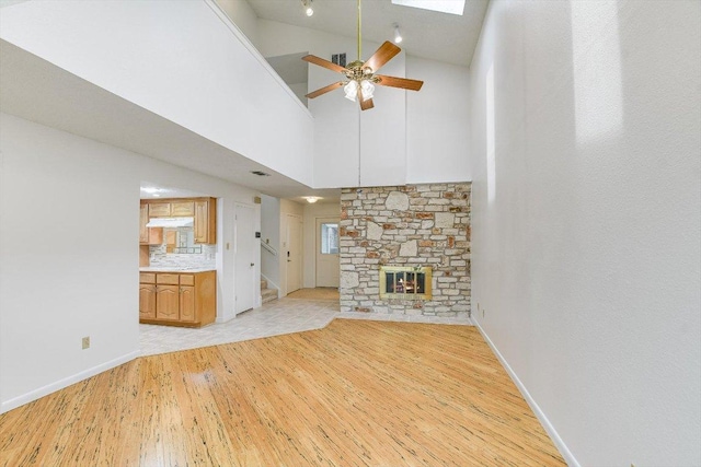 8518 Fathom Cir Unit 107, Austin, TX 78750 - unfurnished living room featuring light wood-style flooring, ceiling fan, stairway, a fireplace, and baseboards