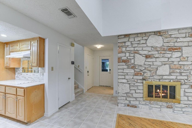 8518 Fathom Cir Unit 107, Austin, TX 78750 - foyer entrance with light tile patterned floors, a textured ceiling, stairway, and a fireplace