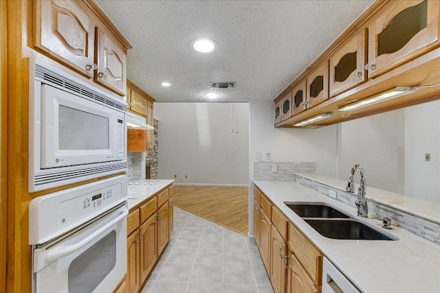 8518 Fathom Cir Unit 107, Austin, TX 78750 - kitchen featuring white appliances, a sink, a textured ceiling, light countertops, and glass insert cabinets