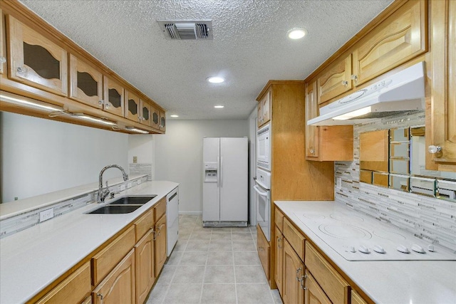 8518 Fathom Cir Unit 107, Austin, TX 78750 - kitchen featuring white appliances, a sink, under cabinet range hood, light countertops, and glass insert cabinets