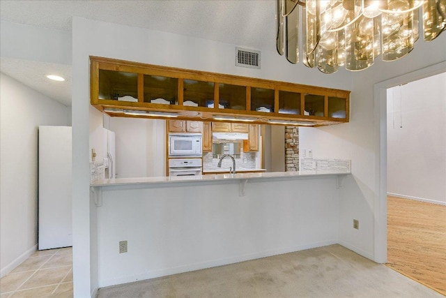8518 Fathom Cir Unit 107, Austin, TX 78750 - kitchen featuring white appliances, under cabinet range hood, light countertops, a chandelier, and a sink