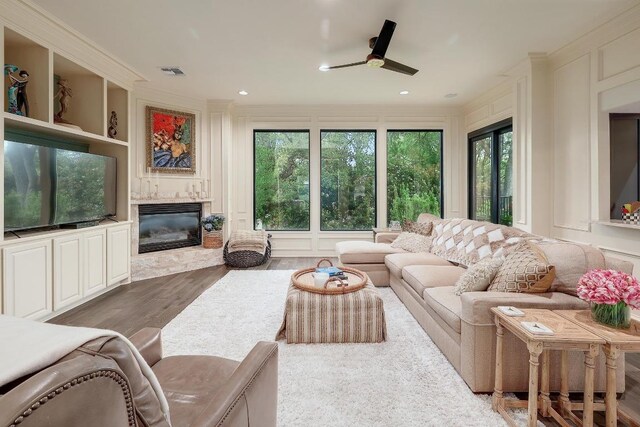 3705 Dogwood Creek Cv, Austin, TX 78746 - living room featuring a high end fireplace, a ceiling fan, wood finished floors, ornamental molding, and a decorative wall