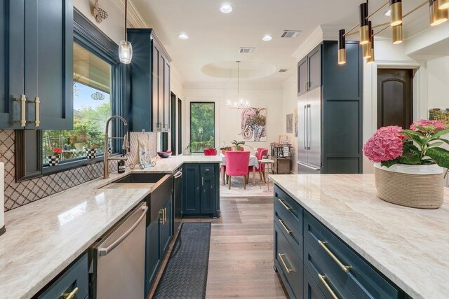 3705 Dogwood Creek Cv, Austin, TX 78746 - kitchen with appliances with stainless steel finishes, wood finished floors, pendant lighting, a chandelier, and blue cabinetry