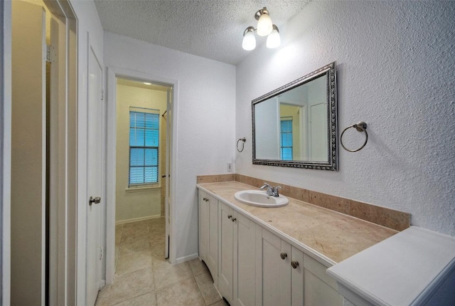 bathroom with tile patterned floors, a textured wall, vanity, and a textured ceiling