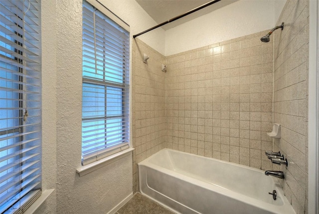 bathroom featuring a textured wall, shower / tub combination, and a wealth of natural light