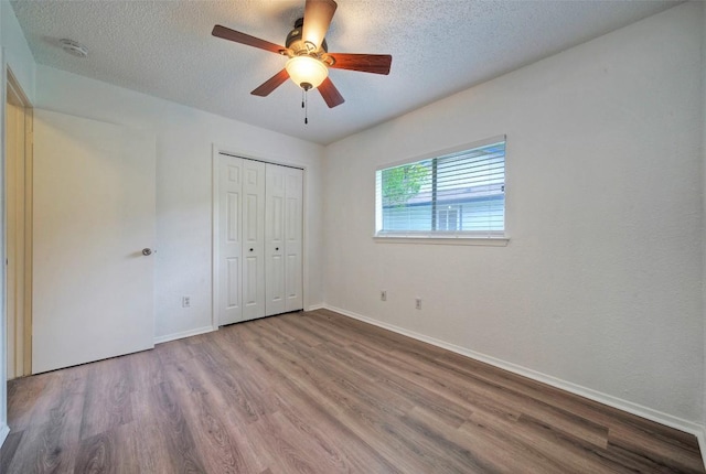 unfurnished bedroom with baseboards, a textured ceiling, and wood finished floors