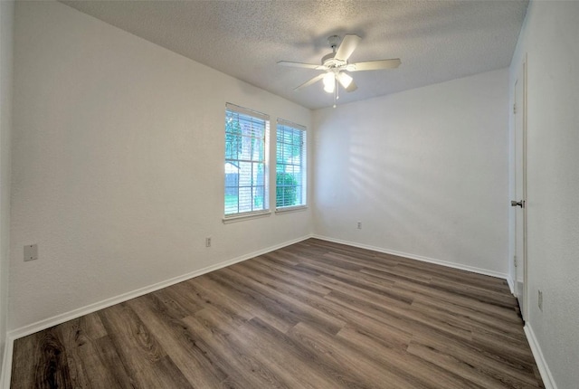 spare room featuring baseboards, a ceiling fan, dark wood-style flooring, and a textured ceiling