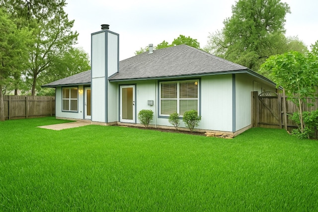 back of property with a shingled roof, a fenced backyard, a gate, a chimney, and a yard
