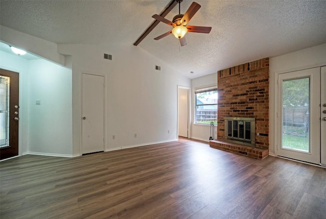 unfurnished living room featuring wood finished floors, vaulted ceiling with beams, a textured ceiling, and visible vents