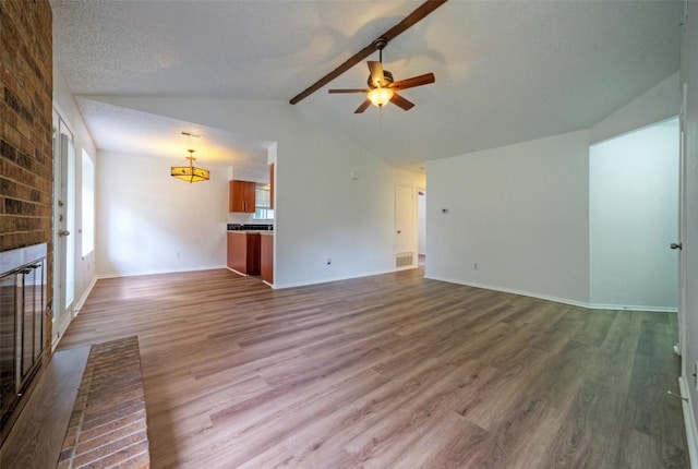 unfurnished living room featuring a fireplace, ceiling fan, lofted ceiling with beams, and dark wood-style floors