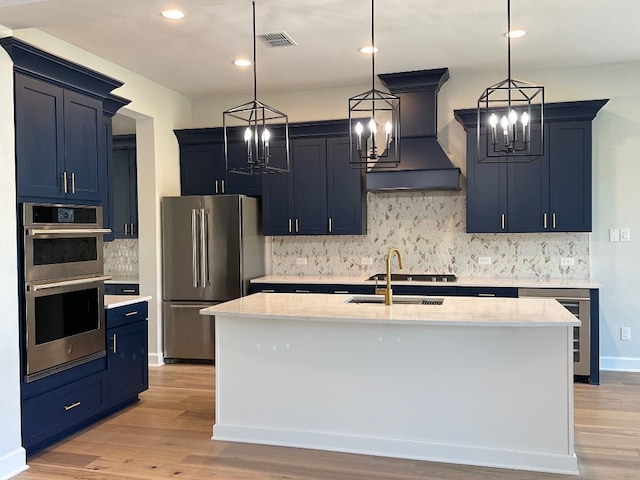 kitchen featuring decorative backsplash, blue cabinetry, custom exhaust hood, an inviting chandelier, and stainless steel appliances