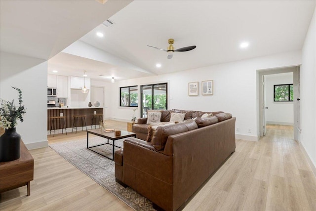 living area featuring light wood-type flooring, ceiling fan, lofted ceiling, and a healthy amount of sunlight
