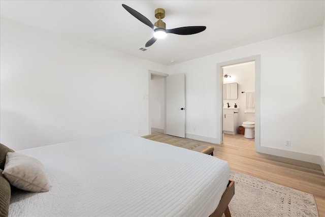 bedroom with visible vents, light wood-style floors, baseboards, ensuite bathroom, and ceiling fan