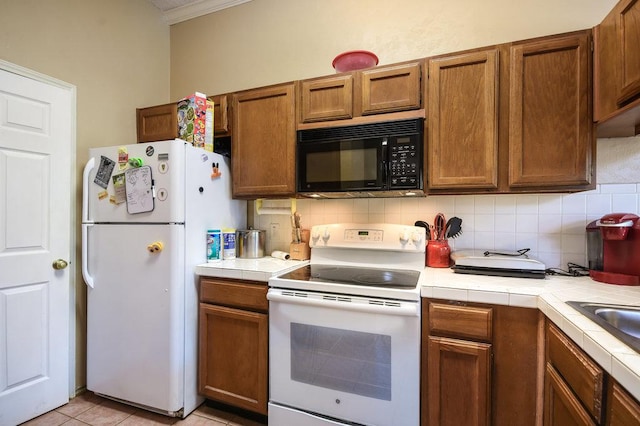 kitchen featuring crown molding, decorative backsplash, white appliances, tile counters, and brown cabinets