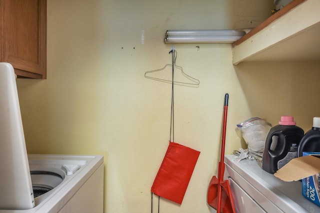 clothes washing area featuring cabinet space and washing machine and clothes dryer