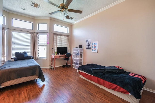 bedroom with crown molding, a textured ceiling, visible vents, and wood finished floors