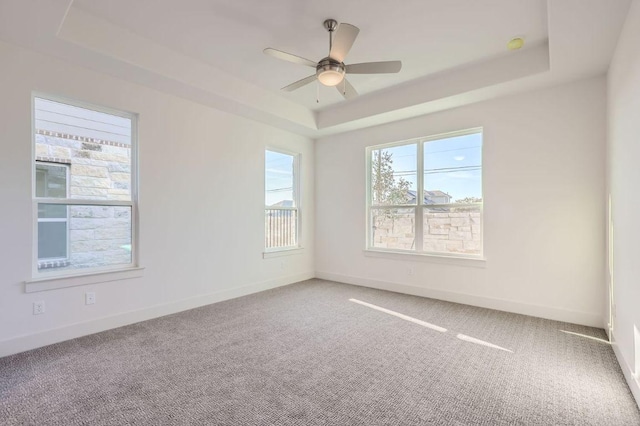 carpeted spare room with baseboards, a ceiling fan, and a raised ceiling