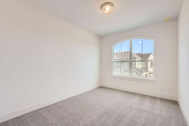 carpeted spare room featuring baseboards