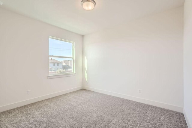 spare room featuring carpet floors and baseboards