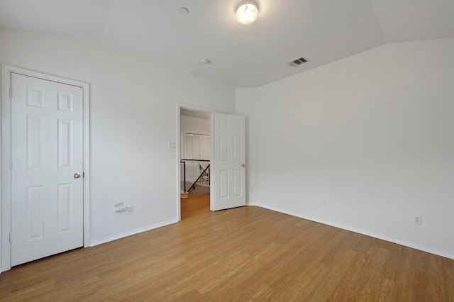 unfurnished bedroom featuring baseboards, visible vents, lofted ceiling, and light wood-type flooring