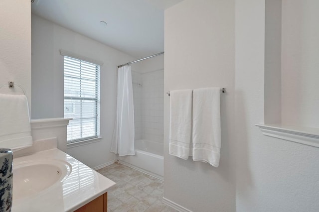 bathroom with vanity, baseboards, a healthy amount of sunlight, and shower / tub combo