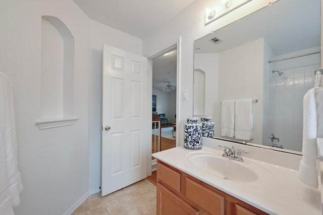 full bath with vanity, a ceiling fan, walk in shower, and visible vents