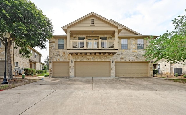 view of front facade with stone siding, an attached garage, driveway, and a balcony