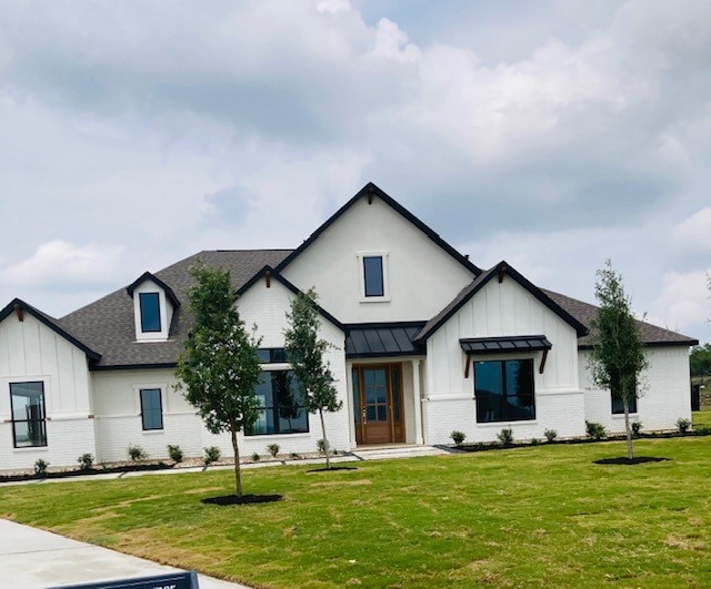216 Cherry Sage Ct, Dripping Springs, TX 78620 - modern inspired farmhouse featuring board and batten siding, brick siding, a front yard, and roof with shingles