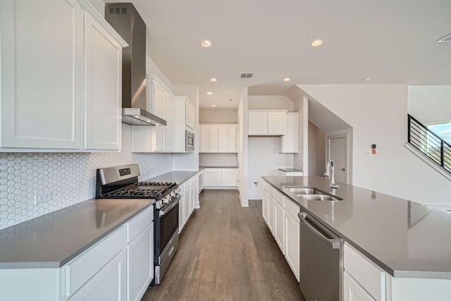 kitchen featuring visible vents, a kitchen island with sink, dark wood-style floors, a sink, and appliances with stainless steel finishes