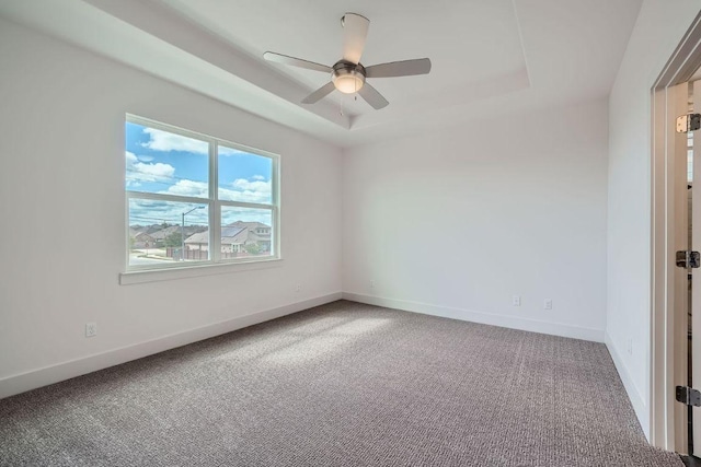 spare room with baseboards, ceiling fan, carpet, and a tray ceiling