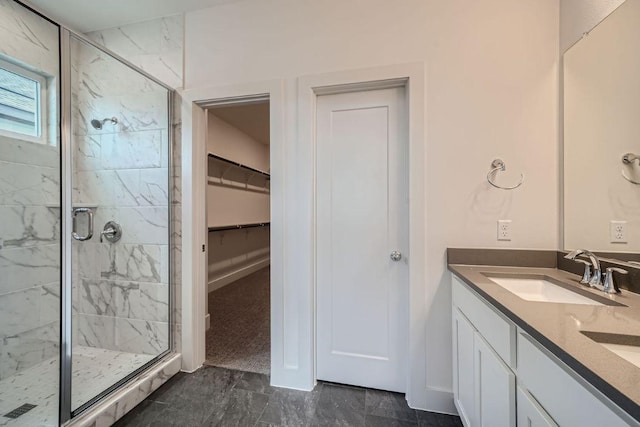 bathroom with double vanity, marble finish floor, a walk in closet, a shower stall, and a sink