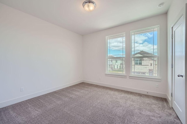 carpeted empty room featuring baseboards