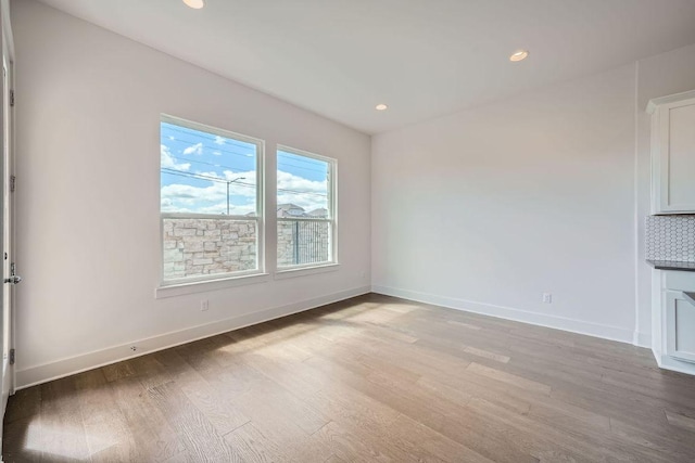 empty room with light wood-style floors, recessed lighting, and baseboards