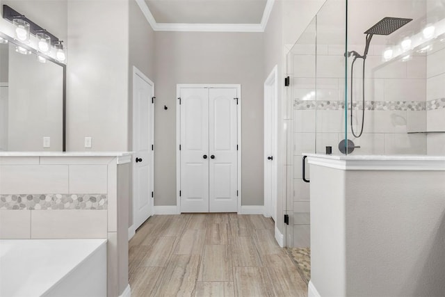 full bathroom featuring wood finished floors, baseboards, tiled shower, ornamental molding, and a tub to relax in