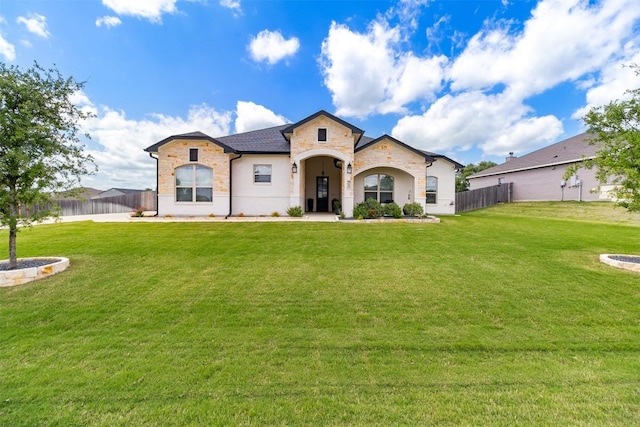 view of front of house featuring a front yard, fence, and stone siding