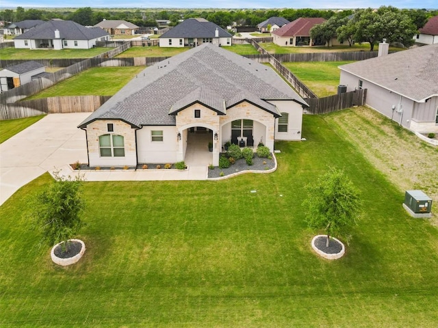 french country style house with a shingled roof, a residential view, a fenced backyard, and stone siding