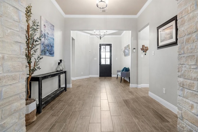 entrance foyer featuring crown molding, baseboards, wood finished floors, and a chandelier