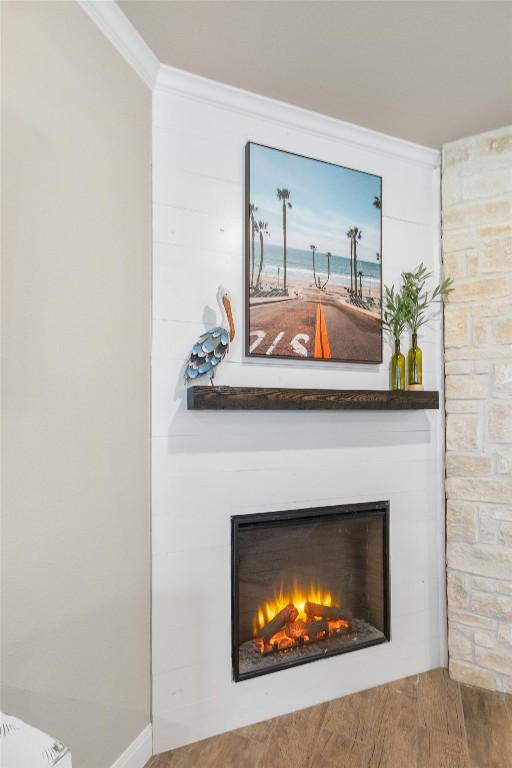 details featuring ornamental molding, wood finished floors, and a large fireplace