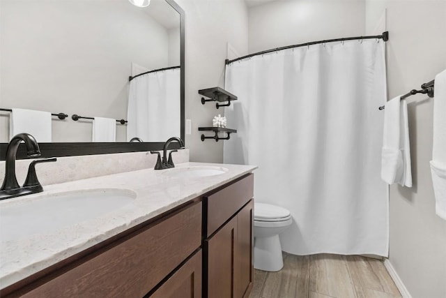 full bathroom featuring double vanity, a sink, wood finished floors, and toilet