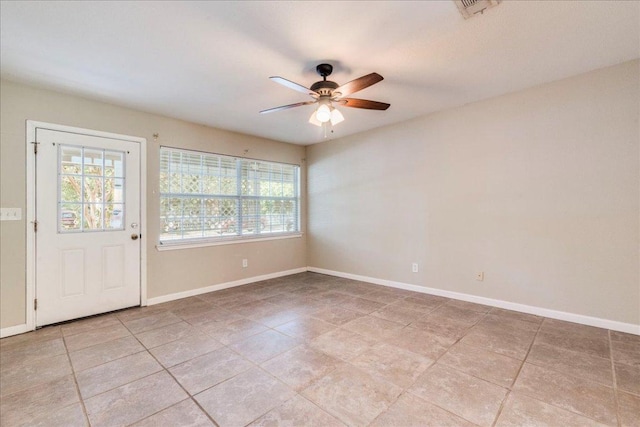 spare room with baseboards, a ceiling fan, light tile patterned floors, and a wealth of natural light