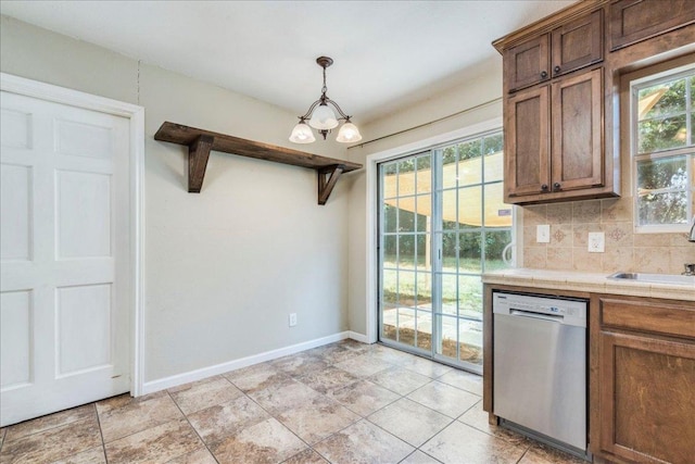 kitchen with decorative backsplash, stainless steel dishwasher, a sink, baseboards, and a notable chandelier